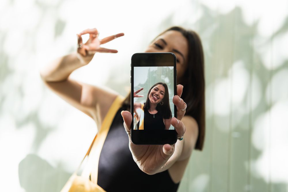 Funny woman taking selfie and showing tongue