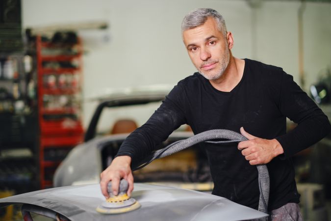 Mechanic grinding paint from car detail