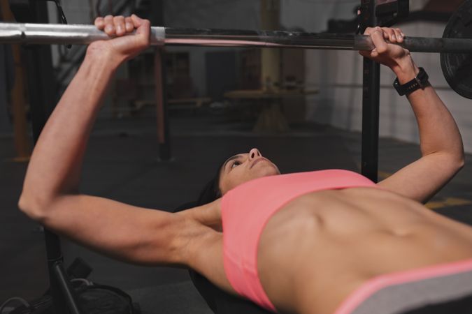 Athletic woman training with barbells in gym