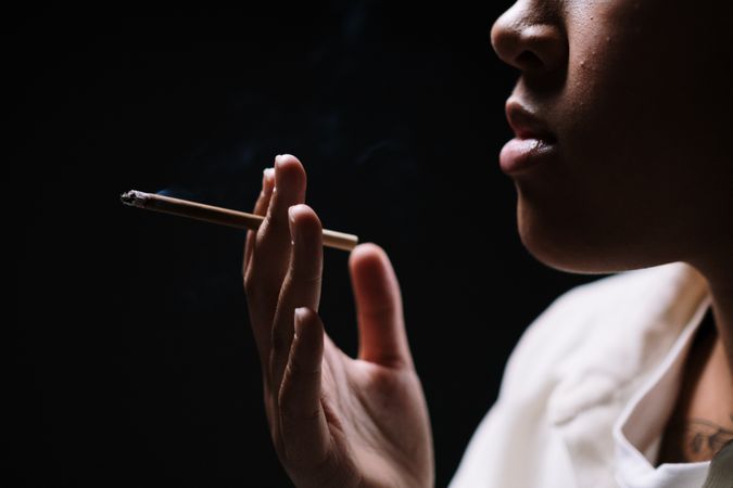 Side view of person smoking cigarette against dark background