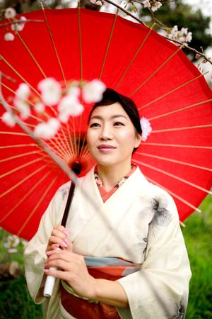 Japanese woman in light kimono holding a red umbrella