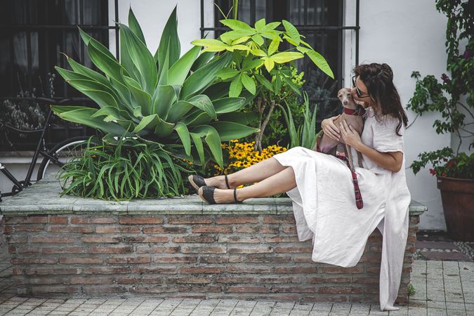 Woman kissing greyhound while relaxing on street