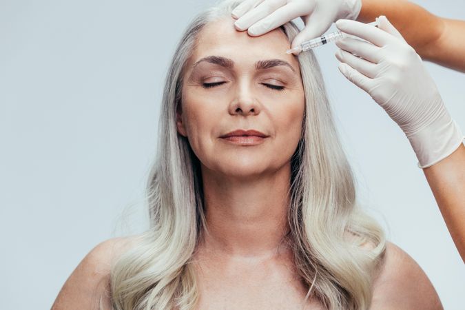 Woman getting anti-aging injection to face by esthetician
