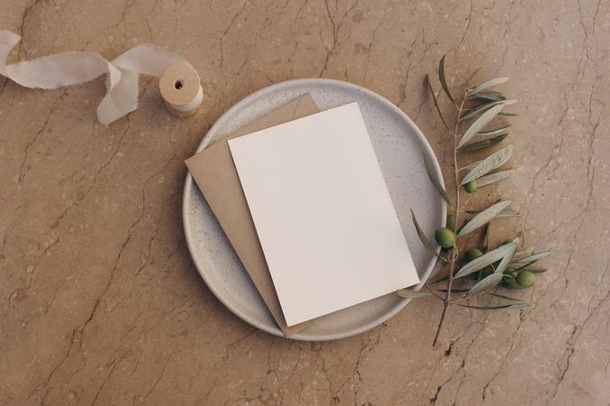 Blank greeting card, invitation and envelope mockup on ceramic plate on marble table