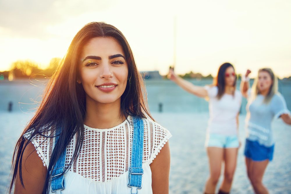 Portrait of smiling brunette woman with friends in background on beach