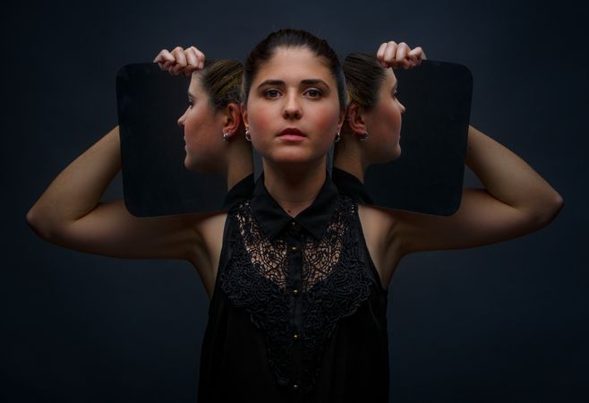 Modern model holding mirrors on sides of face