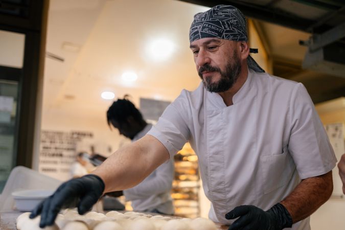 Baker placing balls of dough in a tray