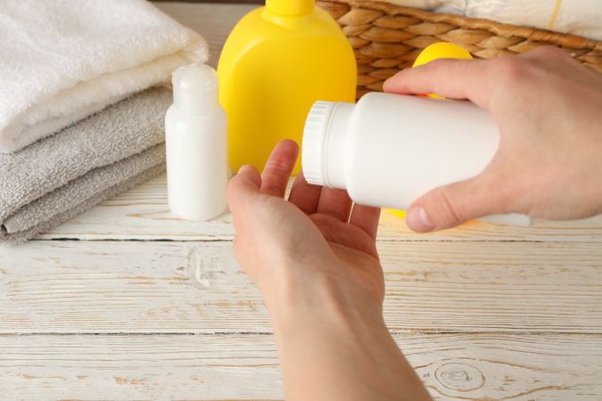 Mom applying talc powder from plastic tube. Baby hygiene