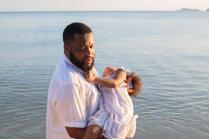 Father playing with daughter above the ocean water