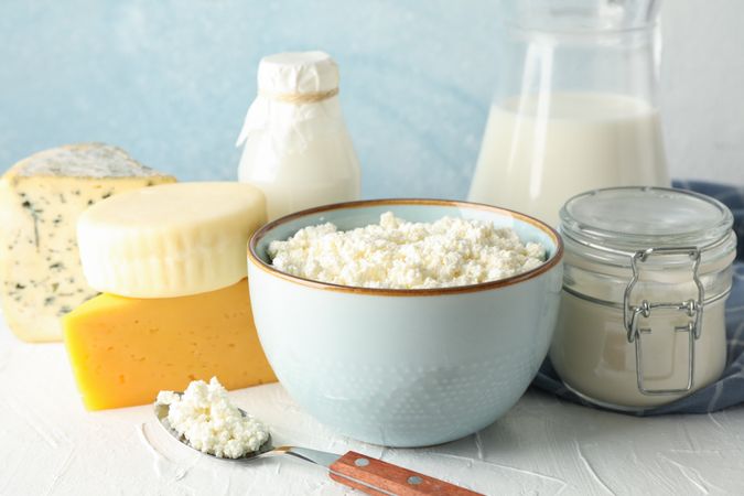 Different dairy products on cream table against blue background