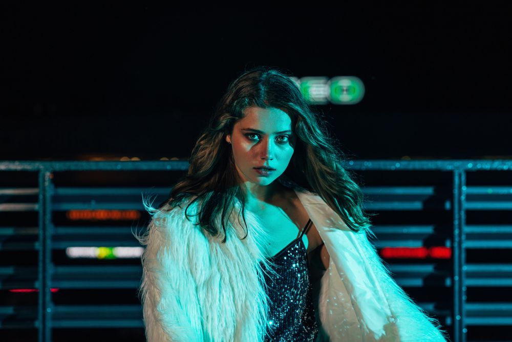 Woman with long hair posing on roof top at night in shaggy faux fur coat