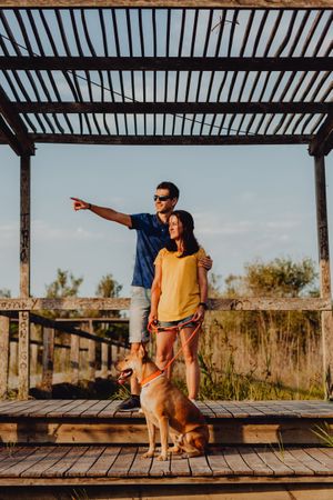 Casual adult couple walking with dog at countryside