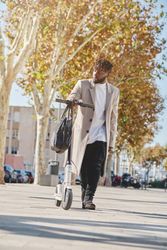 Black male with scooter in autumn city