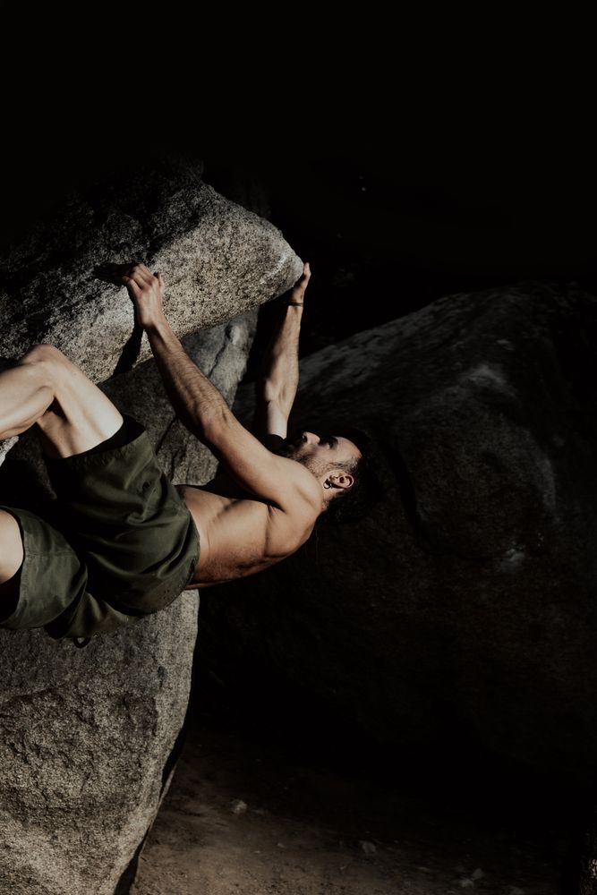 Man practicing rock climbing among large rocks in a forest