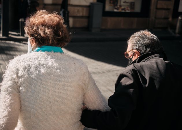 Back of older man and women walking on sunny street in Mexico City