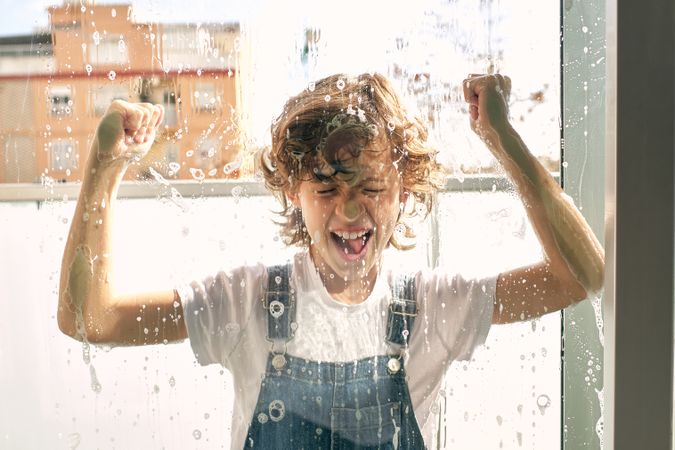 Positive boy knocking on foamy window