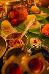 Saffron petals and ladoo surrounded by lit diyas on a table