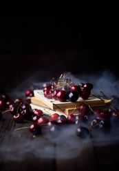 Cherries on top of old books with a layer of thick smoke