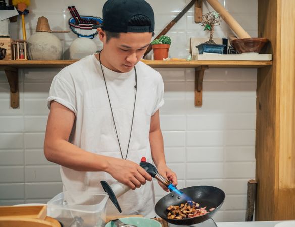 Asian male cooking in kitchen