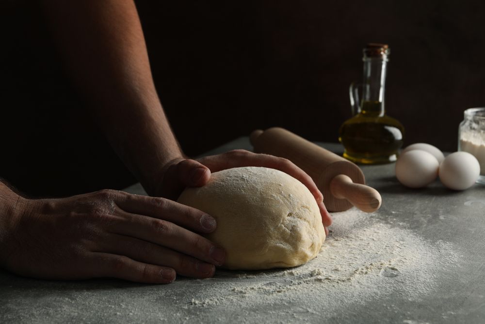 Man cooking dough on gray table, close up