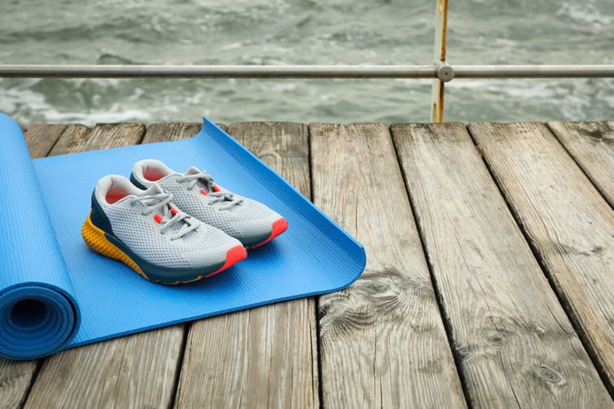 Karemat and sneakers on wooden floor outdoors, space for text