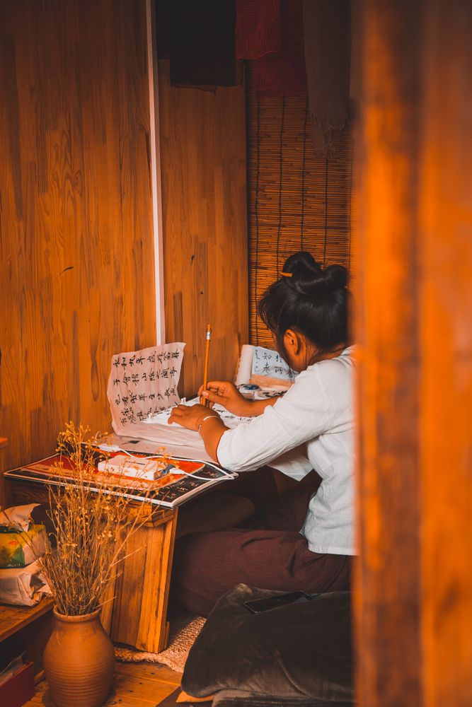 Back view of person sitting on floor desk writing on a paper indoor