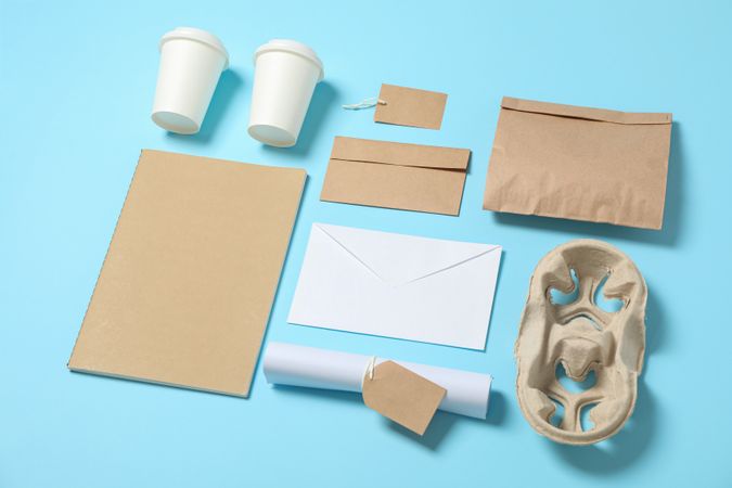 Composition with paper cups and office supplies on blue background, copy space