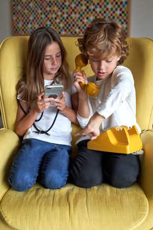 Girl with smartphone near boy with retro telephone