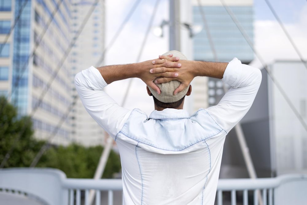 Male in denim standing with hands on head on bridge