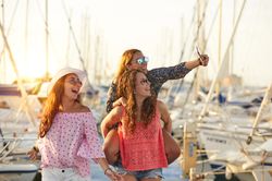 Woman carrying girlfriend on back and taking selfie