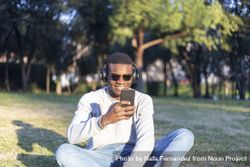 Black male with sunglasses sitting in park checking his phone 5wXm8R