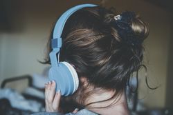 Back view of young woman wearing blue headphone 5wK795
