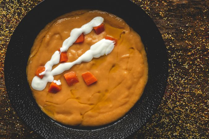 Orange cream soup and sliced carrot in bowl