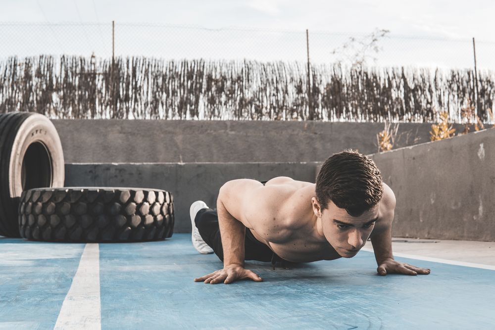 Shirtless male performing push ups on street