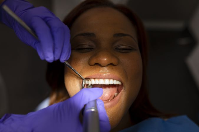 A Black female patient keeps her mouth open mid dental exam