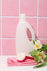 Detergents with fresh flowers on pink background