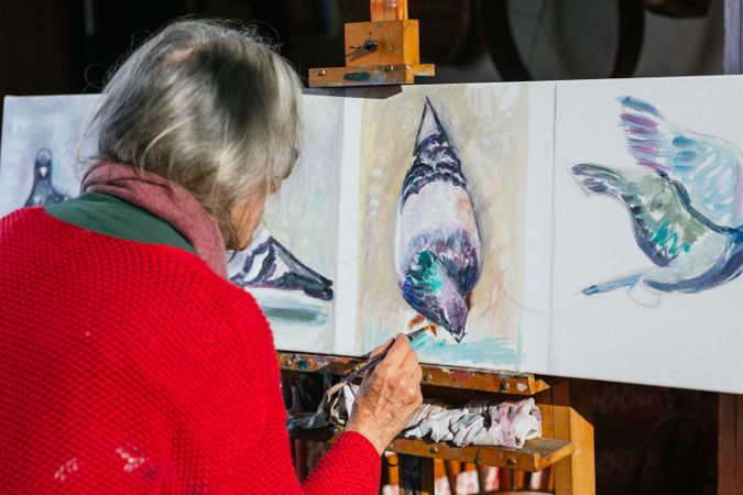 Anonymous woman painting on canvas in garden