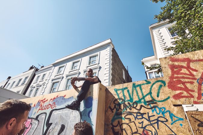 London, England, United Kingdom - August 25th, 2019: Man sitting atop barrier wall with graffiti