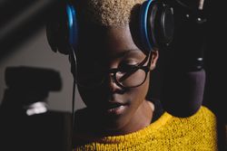 Pensive Black woman in headphones near microphone
