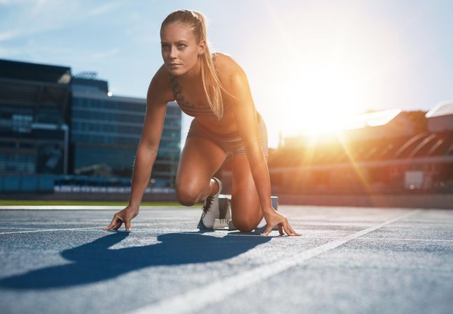 Fit and confident woman in starting position ready for running