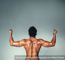 Young man exercising with resistant band on grey background 48Bgqk