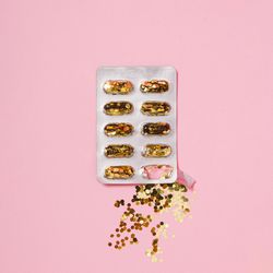 Pill packer with glitter in place of pills on pink background
