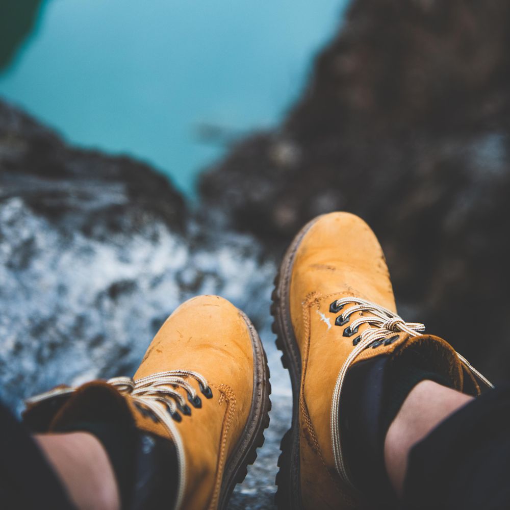 Heavy boots with hills and ocean in the background, square crop