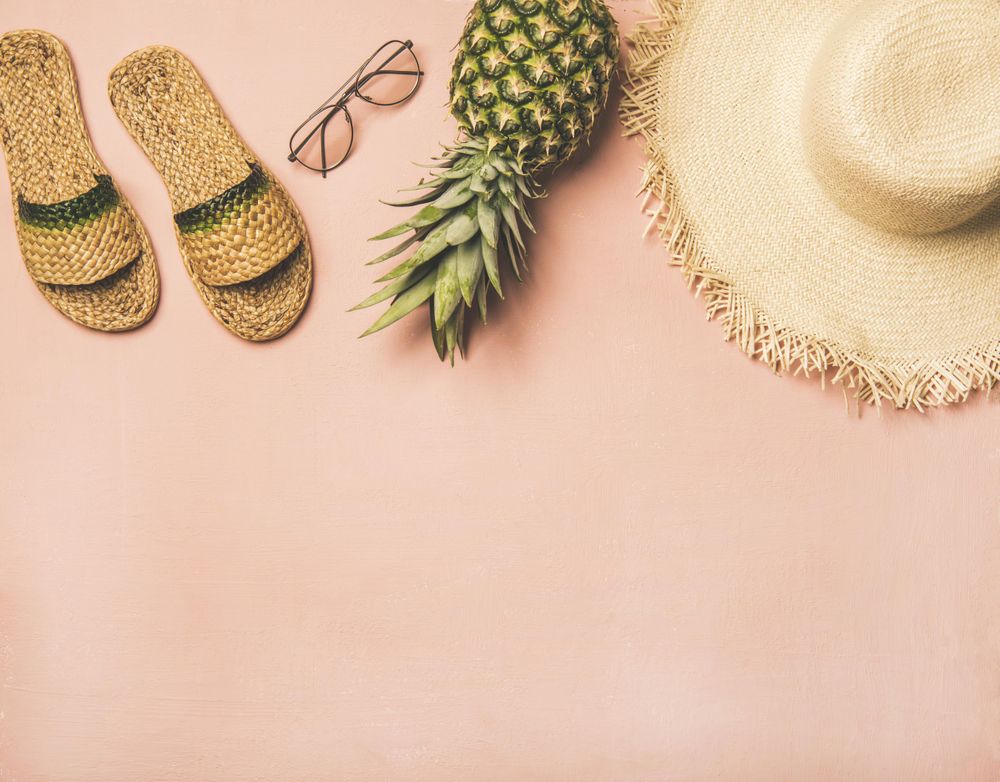 Sandals, glasses, pineapple, straw hat on pink background, with copy space