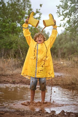 Excited boy playing in puddle in nature