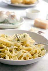 Cooked tagliatelle pasta with pesto sauce on fork