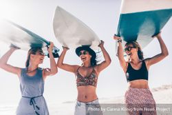 Group of young women holding surfboards overhead 60VVX0
