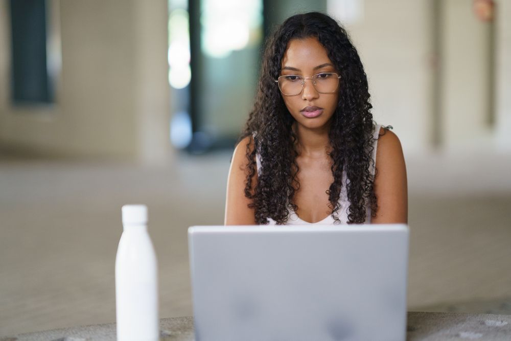 A Young Woman Engaged Actively in Her Online Work Using a Laptop in a Modern Workspace Environment