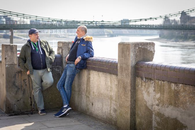 Two male friends hanging out by the river and talking