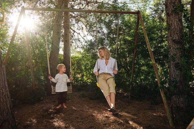 Mother and son sitting on swing in park